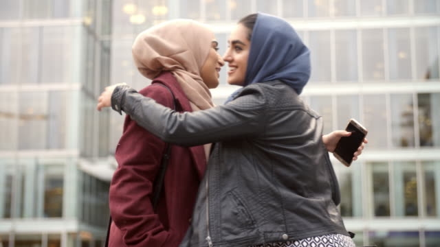 Two British Muslim Women Friends Meeting Outside Office