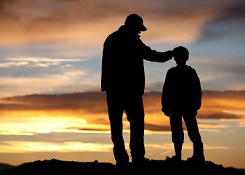 A silhouette of a father and son sharing a tender moment. Additional themes include single parent, parenting, father, fatherhood, stepfather, consoling, care, unity, family, bonding, encouragement, coach, role model, instructor, guidance, and comforting.